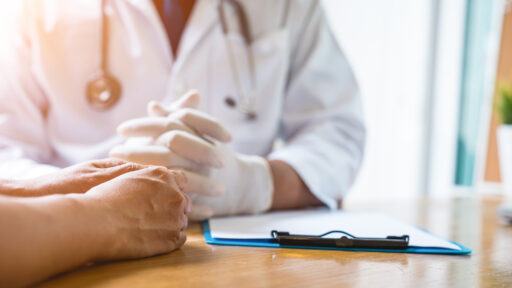 A doctor is working in the hospital, he is wearing a brown stethoscope and he is investigating the illness of the patient.