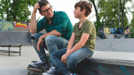 dad talking to his teen son at the park