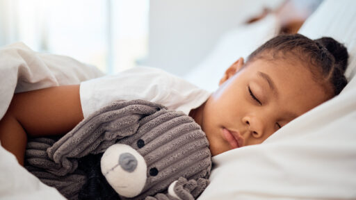 child sleeping in cozy bed with toy teddy bear.
