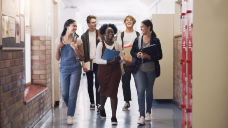 hot of a group of teenagers walking down the hall at high school