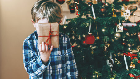 Boy holds up a present in front of his head.