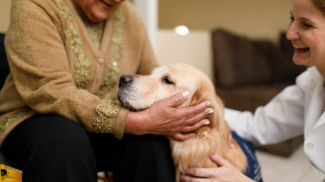 Senior woman and caregiver with therapy dog.