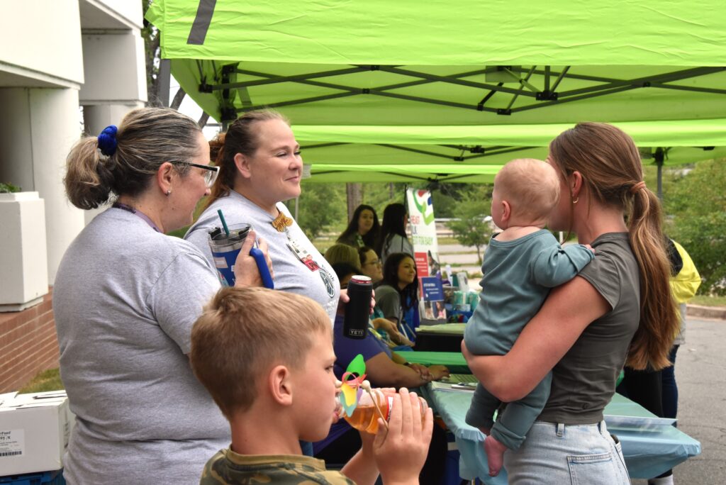 UAMS Milk Bank representative speaking to a young mother holding her baby.