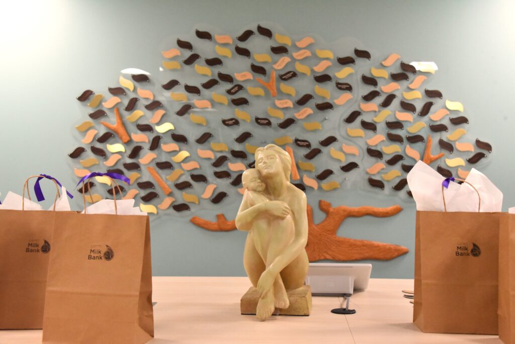 A mother and daughter sculpture on a table in front of a decorative tree.