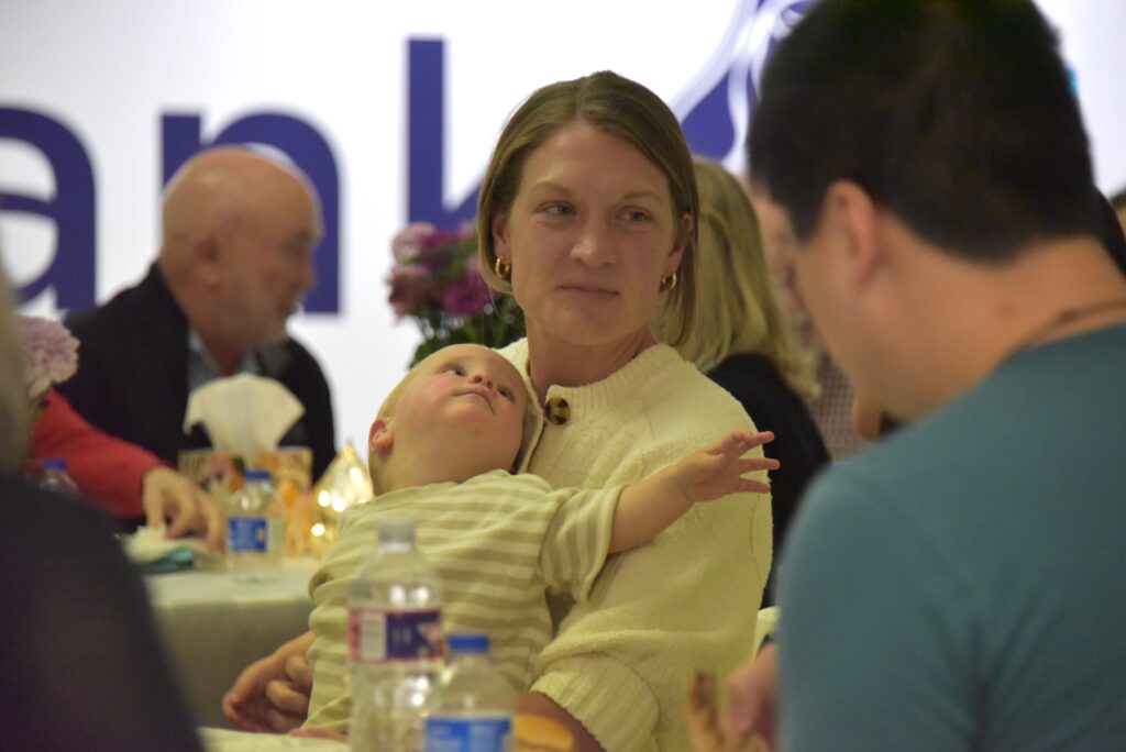 A mother holding her baby listening to others at a table