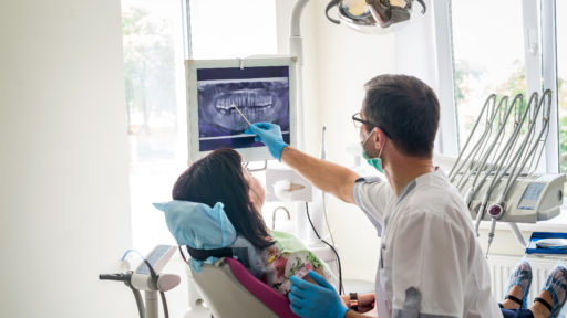 Image of a doctor dentist showing patient's teeth on X-ray.