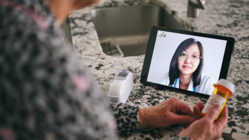 A senior aged woman in her home, talking to a doctor online in a virtual appointment.