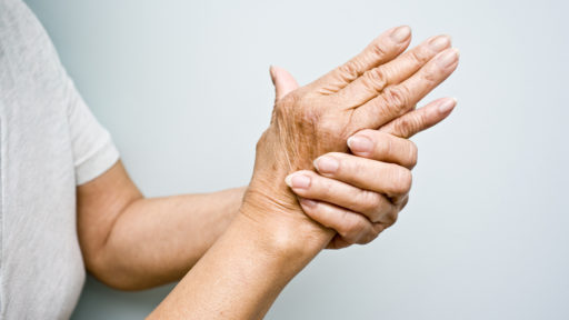 Elderly woman holding her arthritic hands