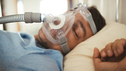 Middle aged man sleeping with Cpap machine mask on for sleep apnea