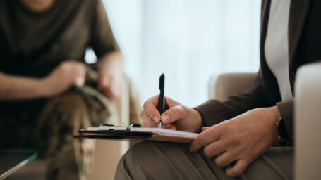 therapist writing notes while talking with patient