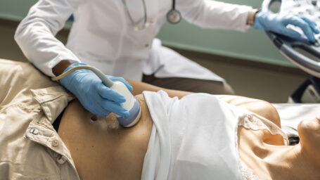 Doctor examining mature woman with ultrasound scanner device