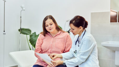 An overweight woman talking with a female doctor about her health