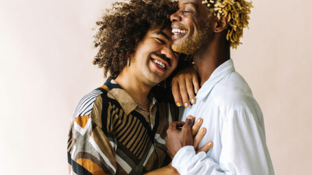 A gay couple enthusiastically embrace in a studio photo shoot