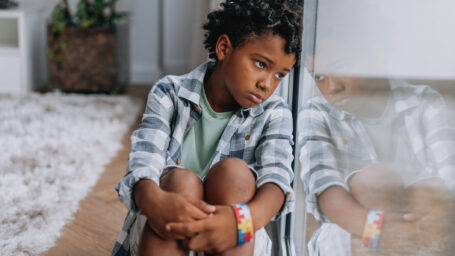 a sad young boy sitting on the floor dealing with anxiety