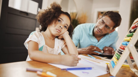 A young girl struggling to do finish her homework with her dad