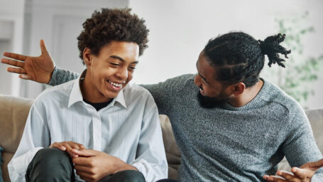 Portrait of a happy teenage boy son talking to his father at home. Sharing secrets and having fun, support and parenthood concept