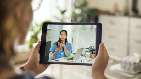 Over the shoulder shot of a patient talking to a doctor using of a digital tablet