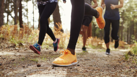 Legs and shoes of four young adults running in forest